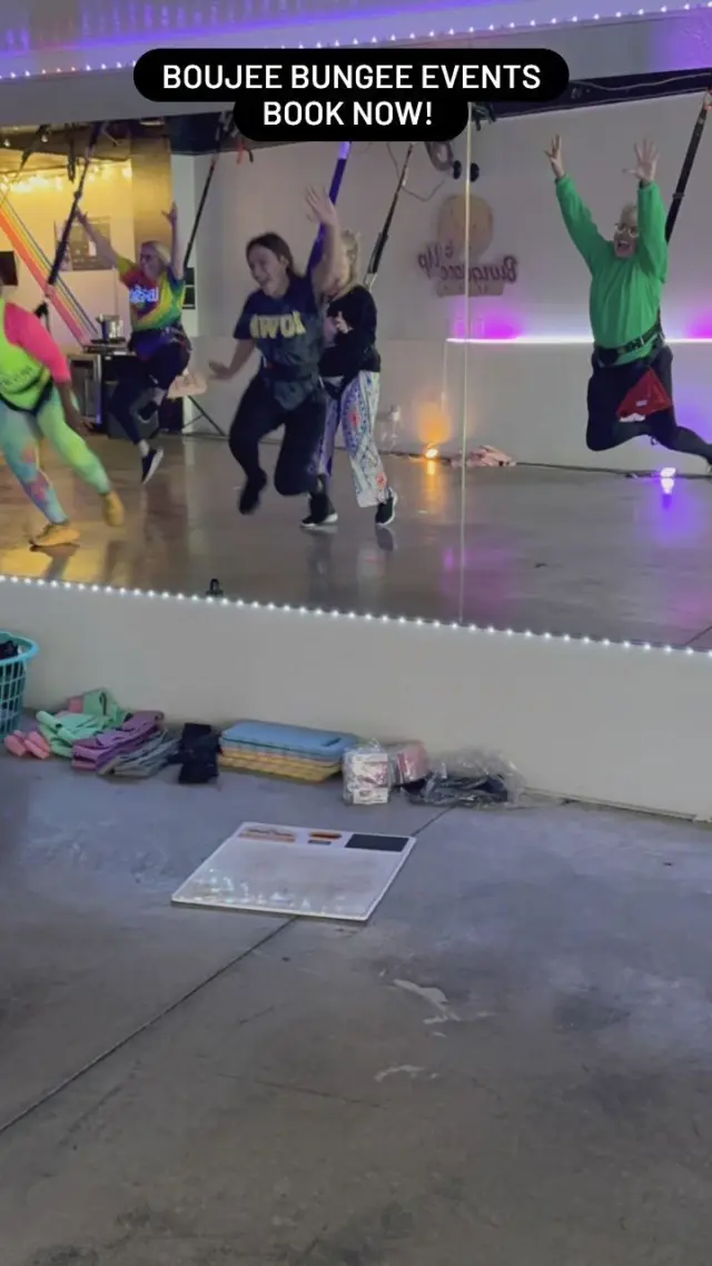 The main Bungee Up studio floor mid-class, four flyers suspended from the ceiling rig in front of the full-length mirror wall