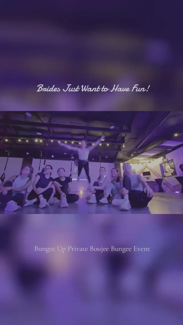 A bridal group mid-routine at a private Boujee Bungee event, bungee stations lit in purple across the studio floor